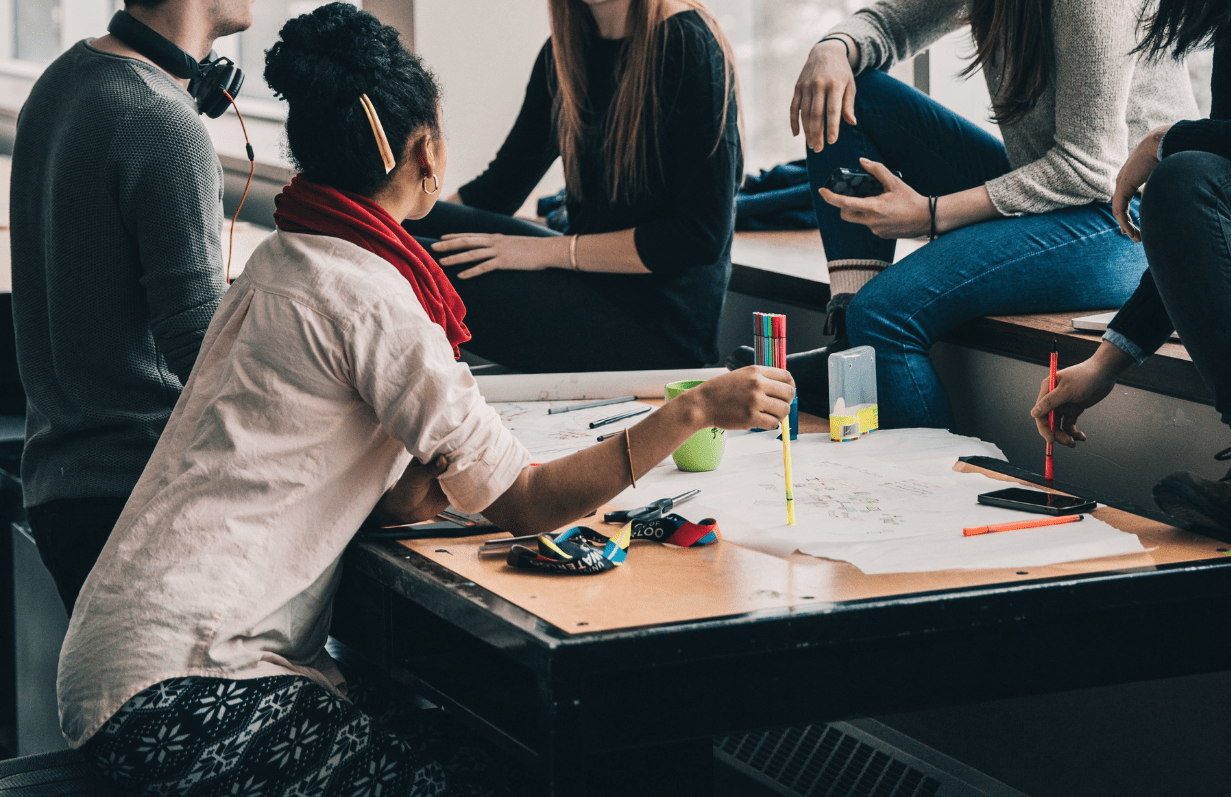 A photograph of a group of people working around a table.