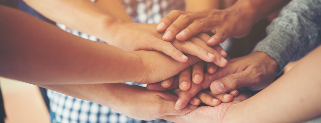 A photograph of a group of 8-10 hands stacked on top of each other.